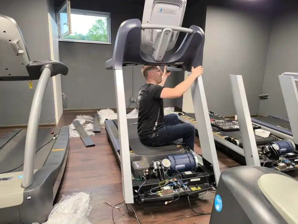 Technician servicing the motor area of a treadmill