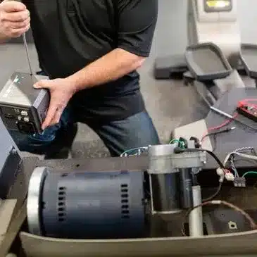 Technician replacing the control unit on a treadmill during service work