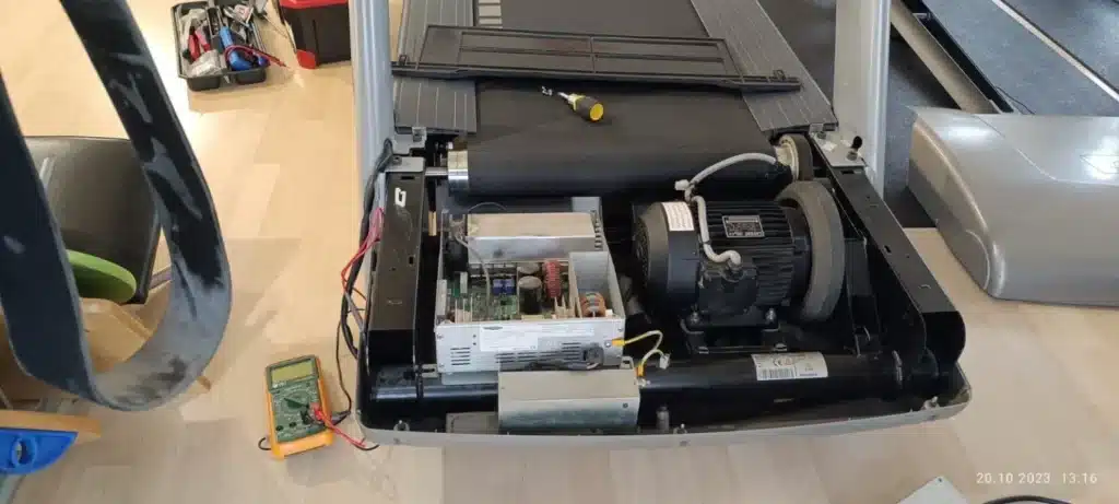 Open treadmill showing motor, PCB, and wiring during service